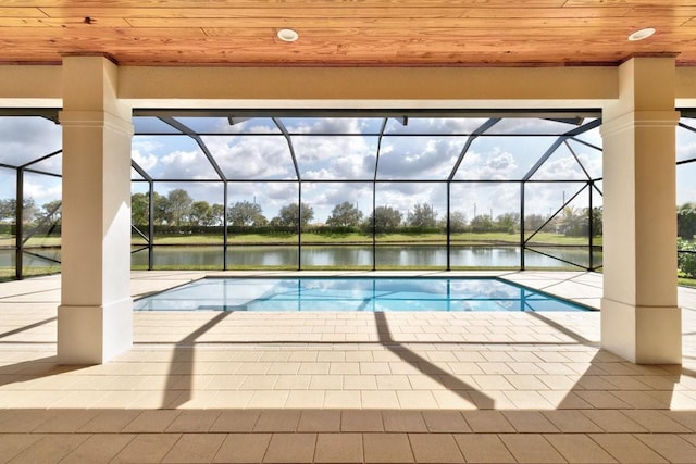 view of swimming pool featuring a water view, glass enclosure, and a patio area