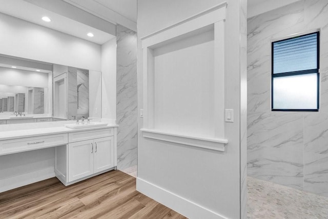 bathroom with hardwood / wood-style flooring, tiled shower, and vanity