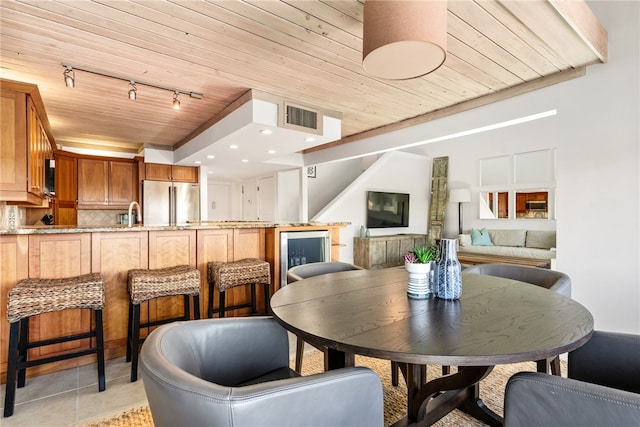 tiled dining area featuring rail lighting and wooden ceiling