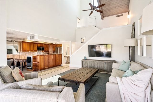 living room with light carpet, wood ceiling, a high ceiling, beverage cooler, and ceiling fan