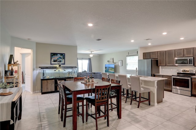 tiled dining space featuring a textured ceiling and ceiling fan