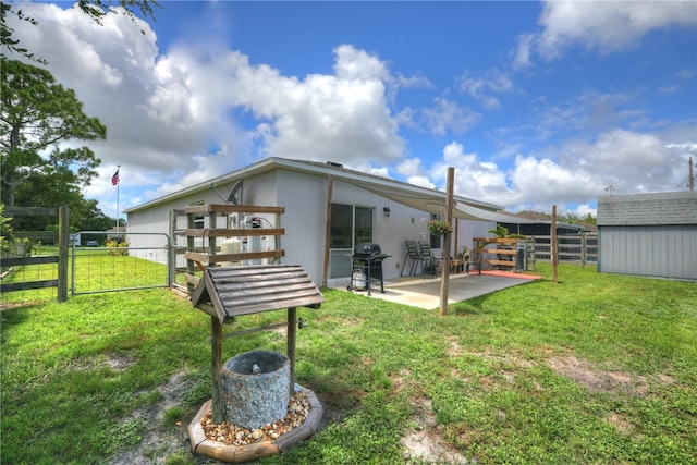 rear view of property with a lawn, an outbuilding, and a patio area