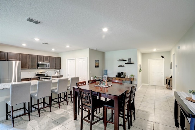 dining area featuring a barn door, a textured ceiling, and light tile patterned floors