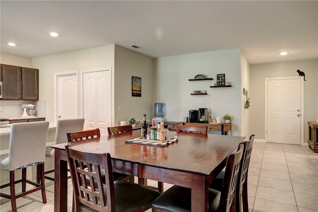 tiled dining room featuring a textured ceiling