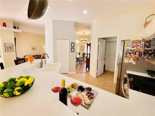 kitchen featuring sink, light tile patterned floors, white cabinetry, stainless steel range with electric cooktop, and kitchen peninsula