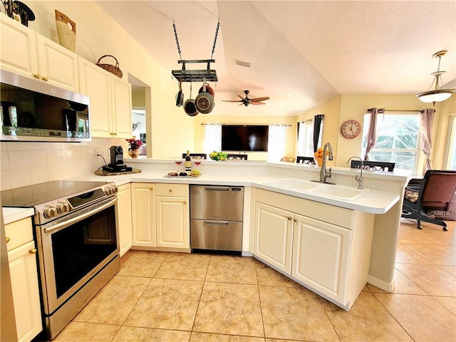 kitchen featuring sink, light tile patterned floors, appliances with stainless steel finishes, decorative backsplash, and kitchen peninsula