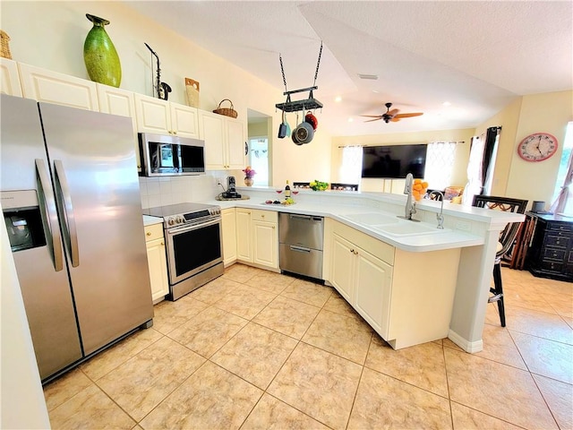 kitchen featuring sink, light tile patterned floors, kitchen peninsula, and appliances with stainless steel finishes