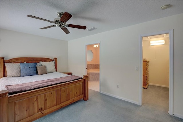 bedroom with ceiling fan, light colored carpet, a textured ceiling, and ensuite bath