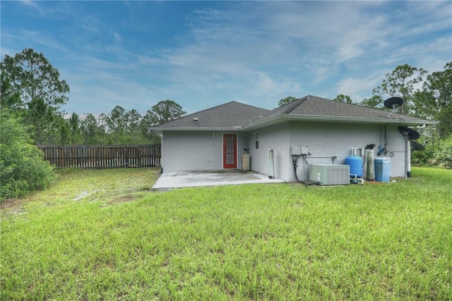 back of property with central AC unit, a patio area, and a lawn