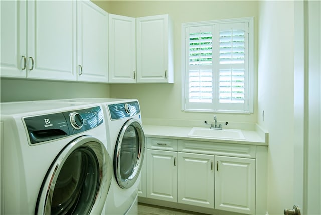 washroom with cabinets, light hardwood / wood-style flooring, sink, and washer and dryer