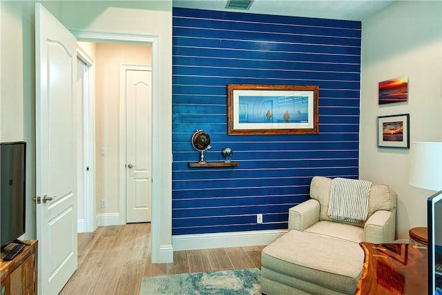 sitting room with wood walls and light hardwood / wood-style flooring