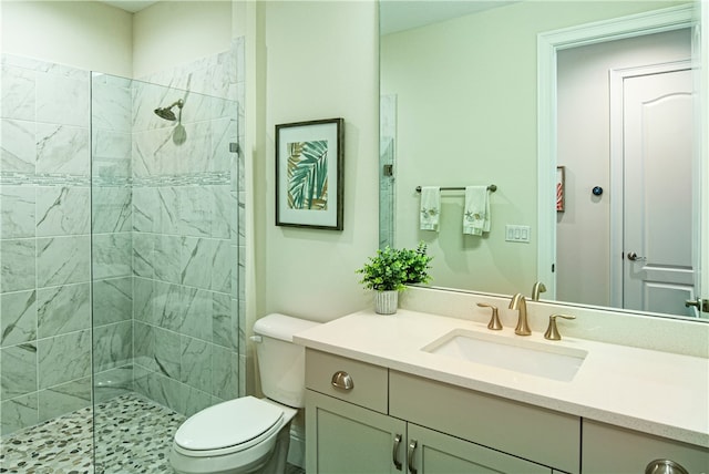 bathroom with vanity, toilet, and a tile shower