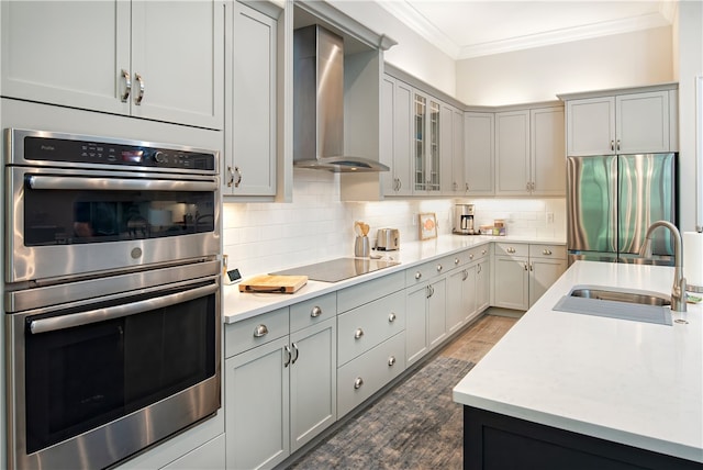 kitchen featuring gray cabinets, appliances with stainless steel finishes, wall chimney exhaust hood, and crown molding