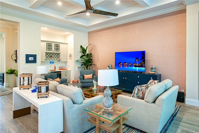 living room with light hardwood / wood-style floors, ceiling fan, beam ceiling, and crown molding