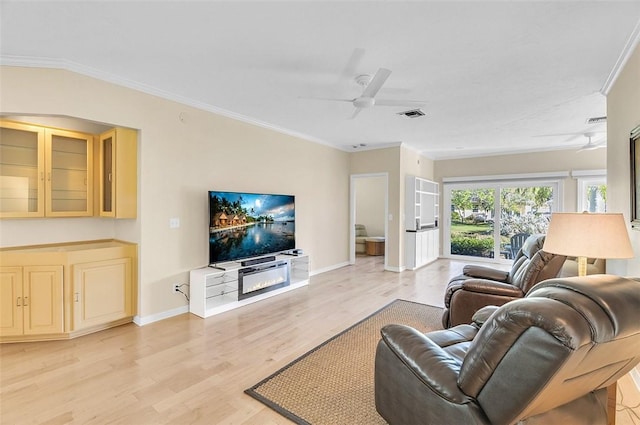 living area featuring visible vents, ornamental molding, a ceiling fan, light wood-style floors, and baseboards