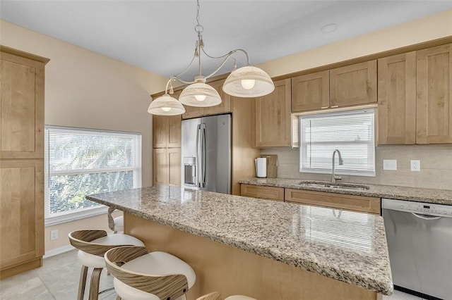 kitchen featuring tasteful backsplash, a kitchen bar, light stone counters, stainless steel appliances, and a sink