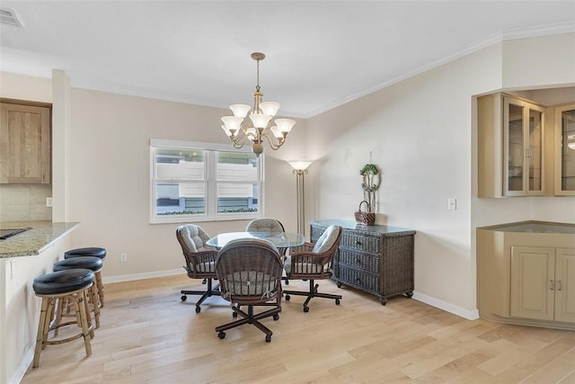 dining room with a notable chandelier, baseboards, light wood finished floors, and ornamental molding