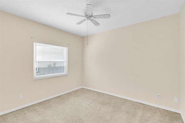 carpeted spare room with a ceiling fan and baseboards