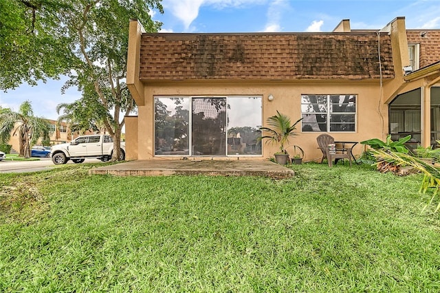 rear view of property featuring a patio area and a lawn