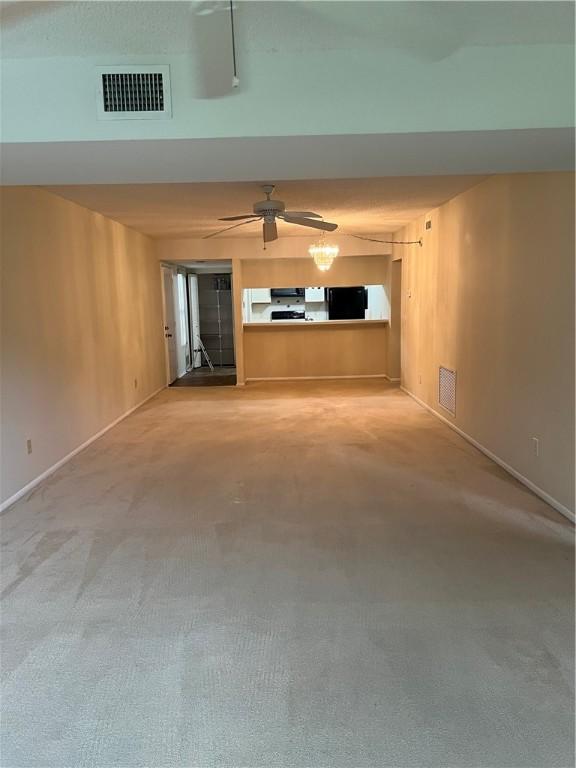 unfurnished living room featuring ceiling fan, visible vents, baseboards, and carpet flooring