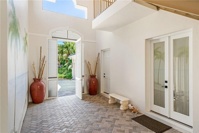 entryway featuring brick floor, a high ceiling, and french doors