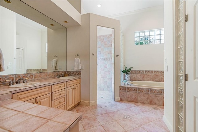 full bathroom with double vanity, a garden tub, a sink, and walk in shower