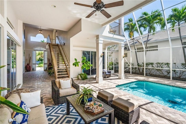 outdoor pool with a ceiling fan, glass enclosure, a patio area, and stairway