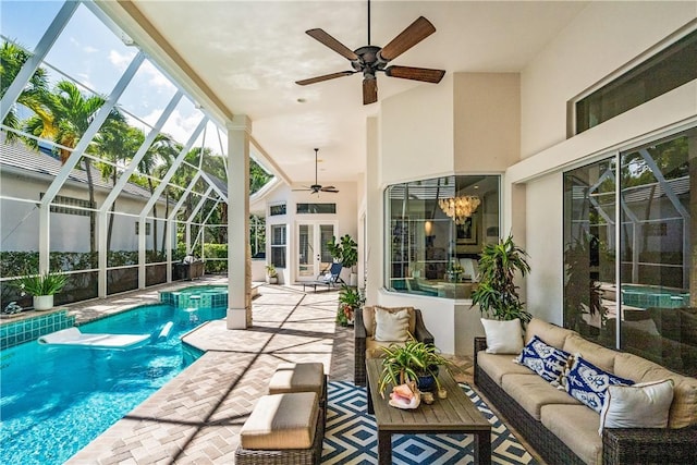 view of swimming pool featuring a patio, a pool with connected hot tub, outdoor lounge area, a ceiling fan, and glass enclosure