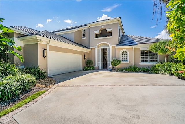 view of front of home featuring concrete driveway, a tiled roof, an attached garage, and stucco siding