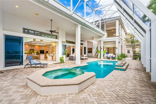 view of pool with an in ground hot tub, ceiling fan, glass enclosure, and a patio area