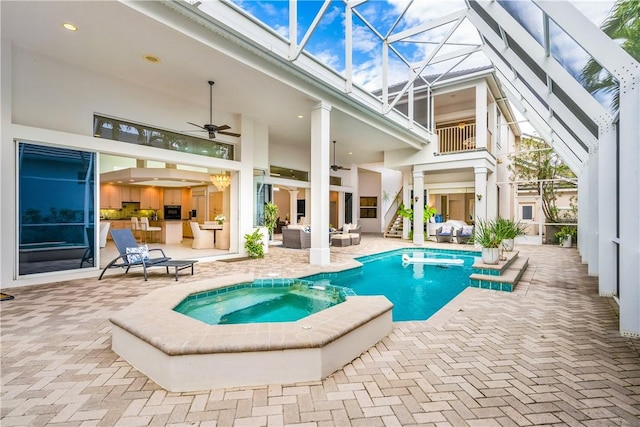 view of swimming pool with a patio, a pool with connected hot tub, outdoor lounge area, ceiling fan, and a lanai