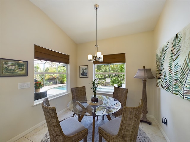 tiled dining room featuring a healthy amount of sunlight, lofted ceiling, and an inviting chandelier