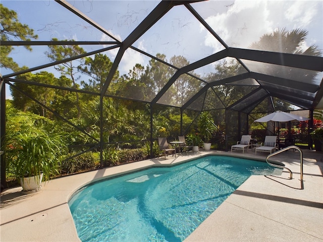 view of pool featuring glass enclosure and a patio