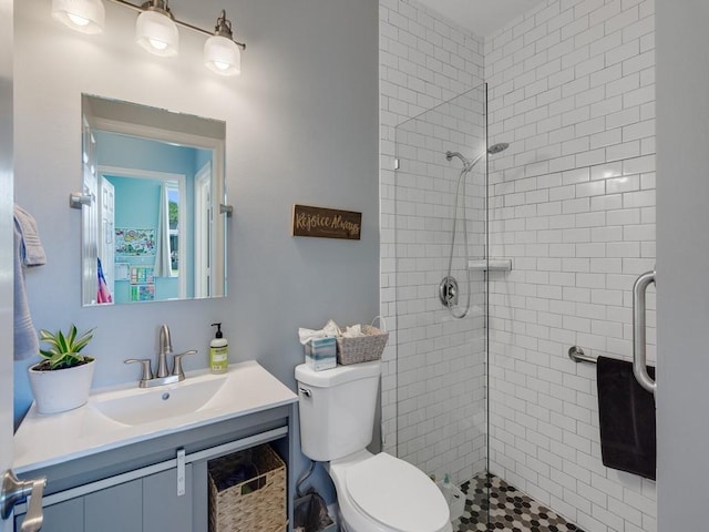 full bath featuring vanity, a tile shower, and toilet