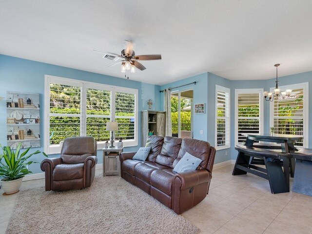 living room featuring ceiling fan with notable chandelier, light tile patterned floors, baseboards, and visible vents