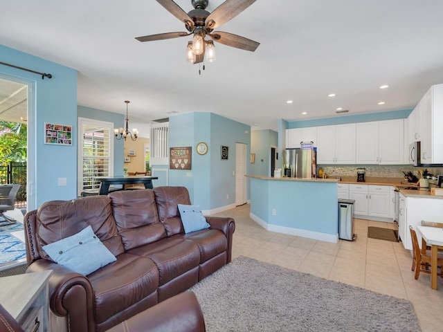 living area featuring light tile patterned floors, baseboards, recessed lighting, and ceiling fan with notable chandelier