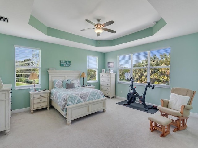 bedroom featuring a tray ceiling, baseboards, carpet flooring, and visible vents