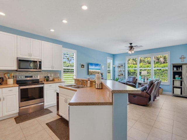 kitchen featuring tasteful backsplash, appliances with stainless steel finishes, light tile patterned flooring, a sink, and open floor plan