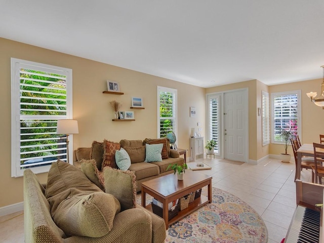 living area with light tile patterned floors, a wealth of natural light, a notable chandelier, and baseboards