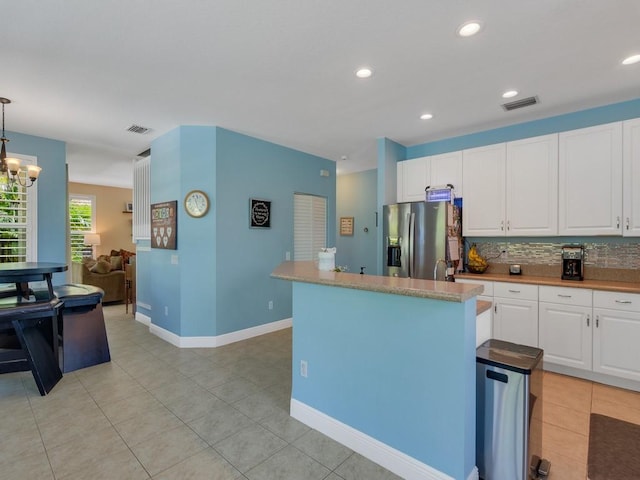 kitchen with stainless steel fridge with ice dispenser, tasteful backsplash, visible vents, and white cabinetry