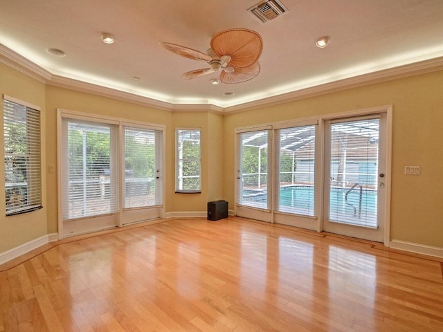 doorway to outside with crown molding, light wood finished floors, visible vents, ceiling fan, and baseboards