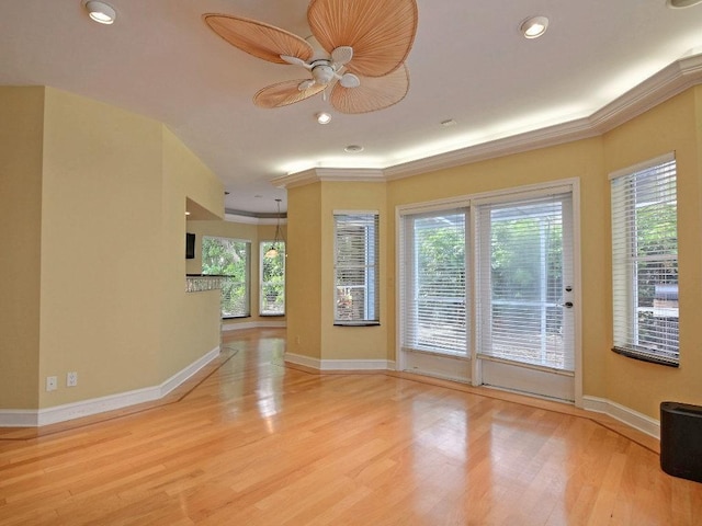 empty room with ornamental molding, plenty of natural light, wood finished floors, and baseboards