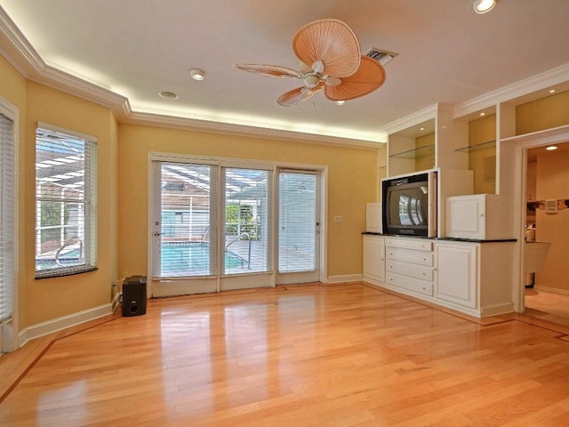 kitchen with a ceiling fan, white cabinets, light wood-style floors, dark countertops, and crown molding