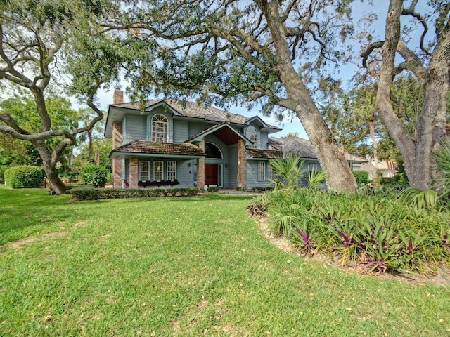 traditional-style home featuring a chimney and a front lawn