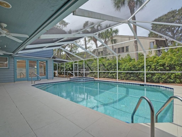 view of swimming pool with a patio, a pool with connected hot tub, glass enclosure, and a ceiling fan