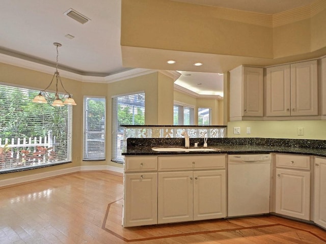 kitchen featuring white dishwasher, a sink, visible vents, ornamental molding, and light wood-type flooring