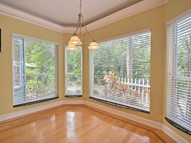 unfurnished dining area featuring a healthy amount of sunlight, baseboards, ornamental molding, and wood finished floors