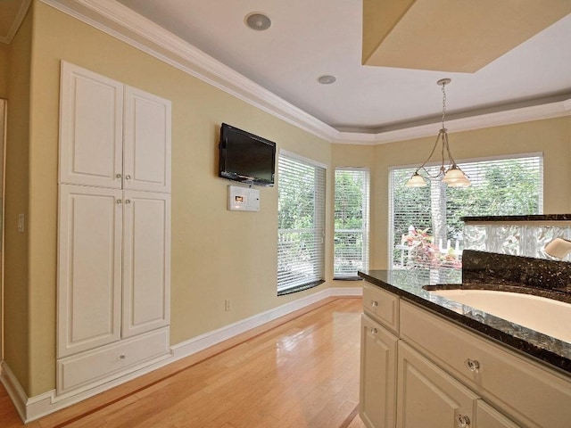 kitchen featuring decorative light fixtures, light wood-type flooring, a wealth of natural light, and crown molding