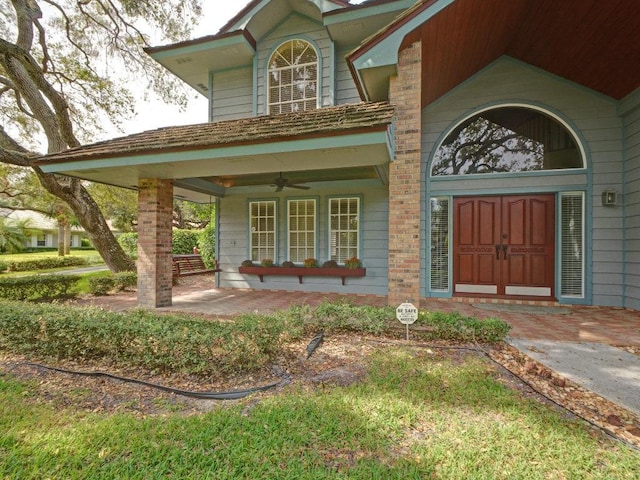 view of exterior entry with a ceiling fan and covered porch