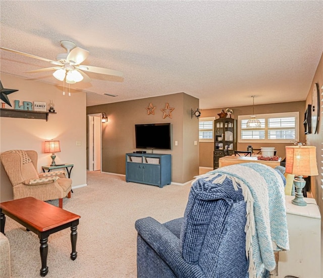 living area with carpet floors, ceiling fan, a textured ceiling, and baseboards